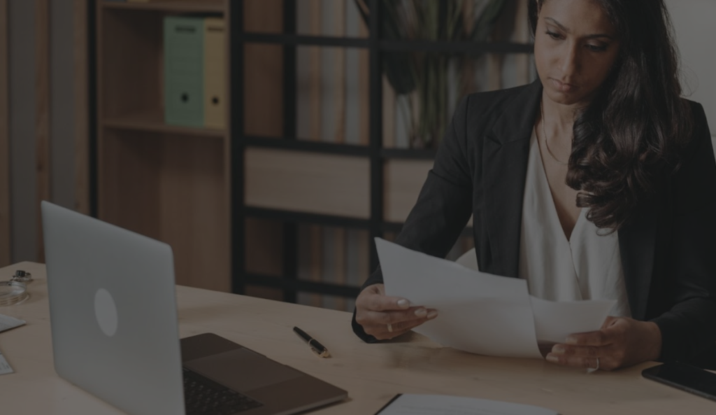 A focused woman sitting at a desk, intently reading a document.