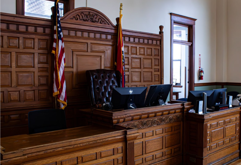 An empty courtroom with wooden benches and a judge's bench.